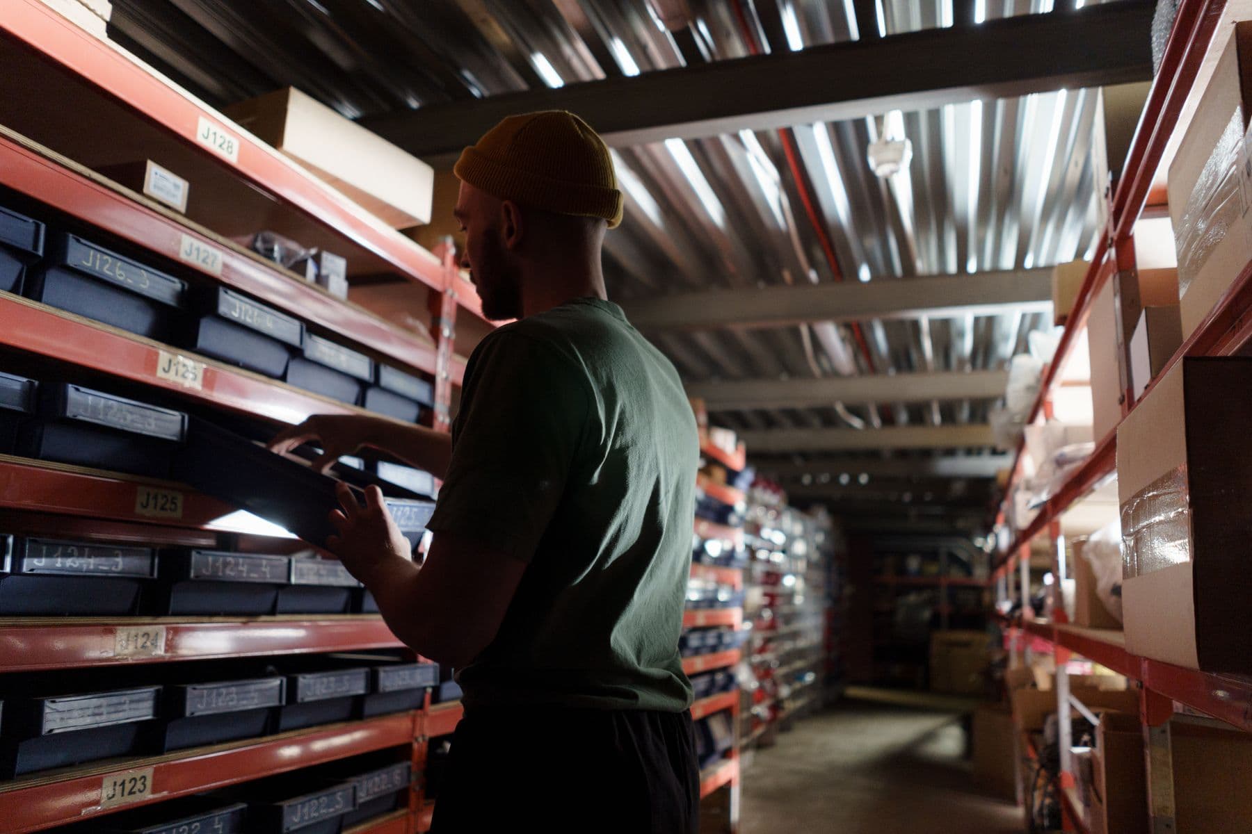 Stock controller checking items along shelving in a storeroom