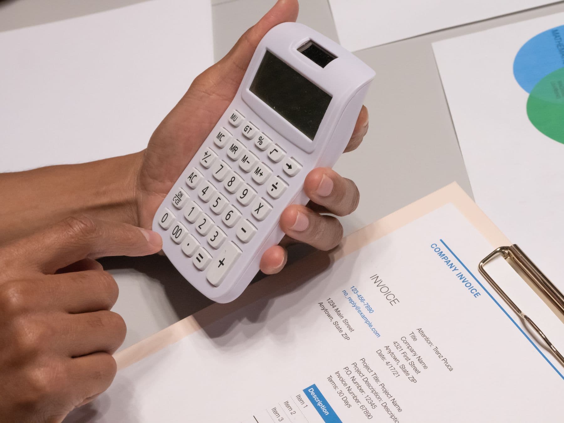 Hands working through a commercial invoice with a calculator