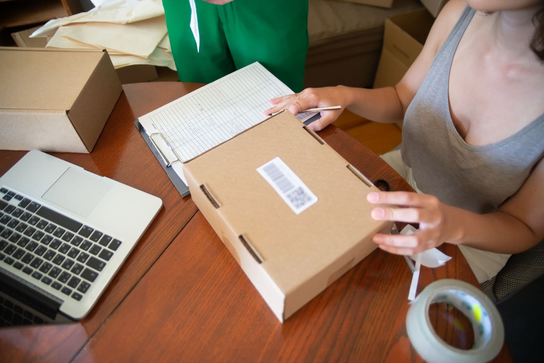 Small business owner packing an online order beside a laptop