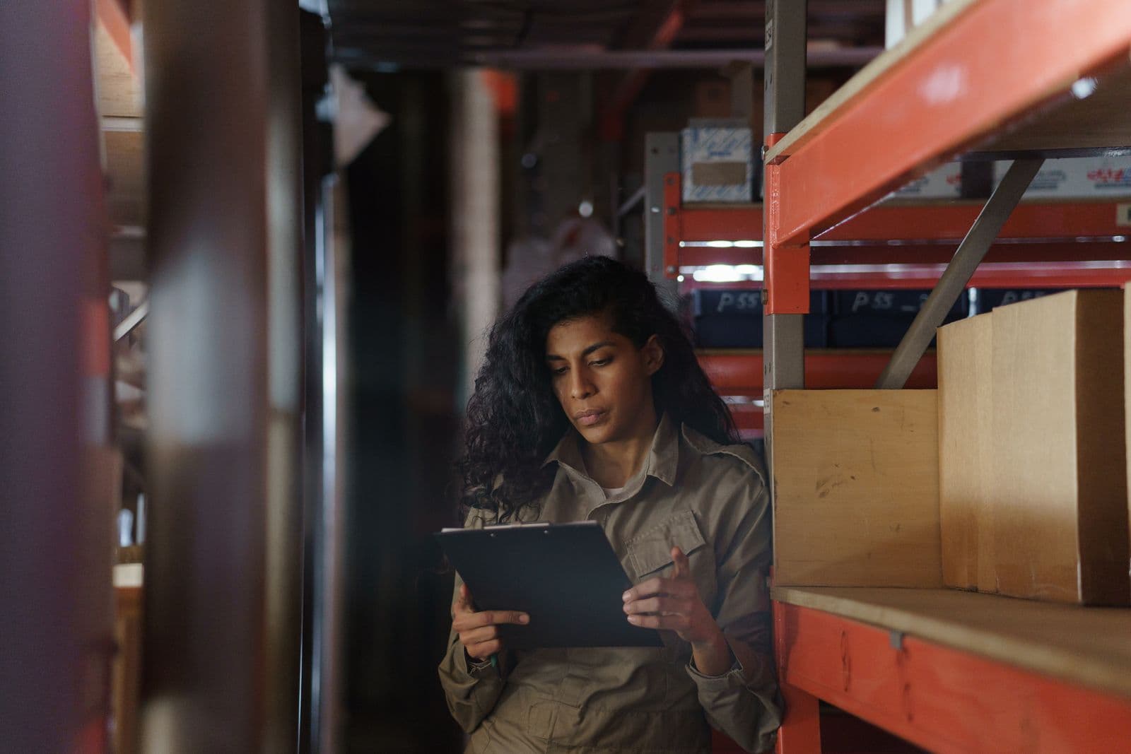 Stock controller checking inventory records in a warehouse aisle at a growing SME